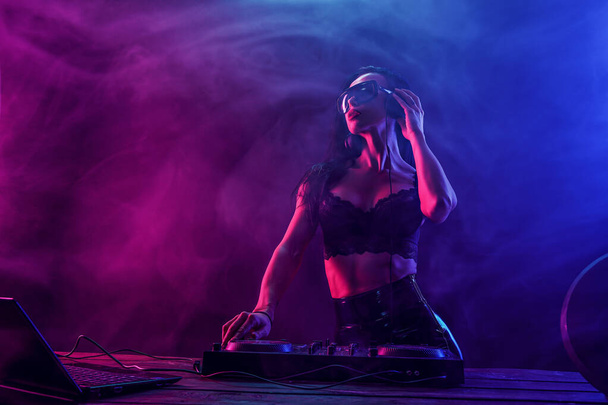 Young sexy woman dj playing music. Headphones and dj mixer on table. - Fotografie, Obrázek