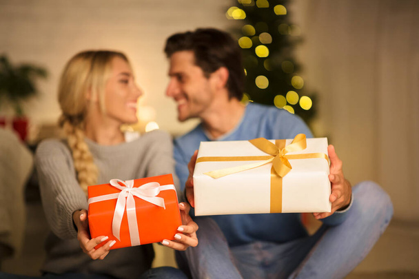 Preciosa pareja estirando cajas de regalo a la cámara
 - Foto, imagen