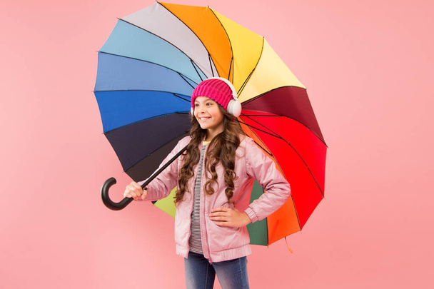 Entertain yourself. Fun concept. Feeling good. Girl having fun walking wireless headphones under colorful umbrella. Fall leisure. Music always with me. Every day fun. Child enjoying simple things - Photo, Image