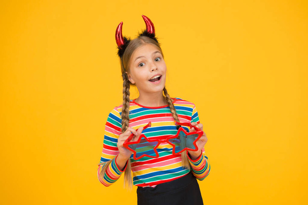 Start this party. Party attributes. Playful demon girl. Small child with red horns and eyewear. Accessories for carnival. Girlish temper. Cute but dangerous. Halloween concept. Preparing for party - Foto, Bild