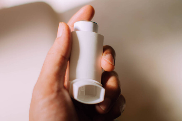 ein junger Mensch hält ein Asthma-Inhalationsgerät in der Hand - Foto, Bild