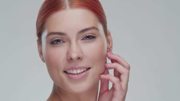 Studio portrait of young, beautiful and natural redhead woman applying skin care cream. Face lifting, cosmetics and make-up. - Metraje, vídeo