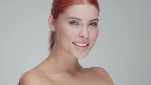 Studio portrait of young, beautiful and natural redhead woman applying skin care cream. Face lifting, cosmetics and make-up. - Záběry, video
