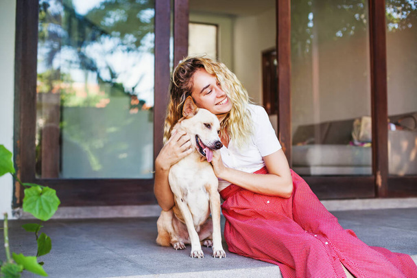 Beautiful caucasian woman hugging her mongrel dog pet in front of her house - Foto, imagen