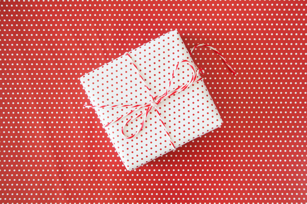 White gift with ribbon on the red polka dot background - Φωτογραφία, εικόνα
