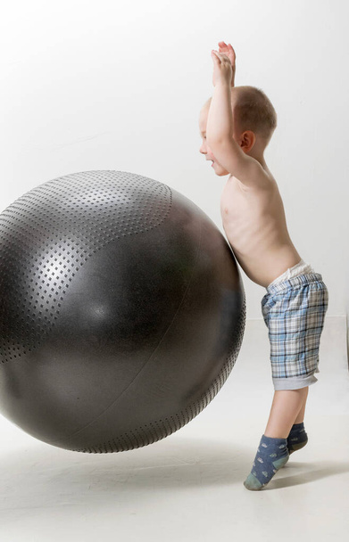 Cute boy plays with a big ball for fitness - 写真・画像