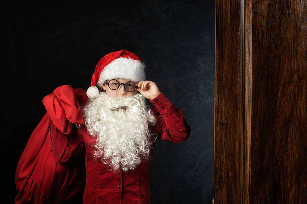 Portrét chlapce v obraze Santa Clause na tmavém pozadí . - Fotografie, Obrázek