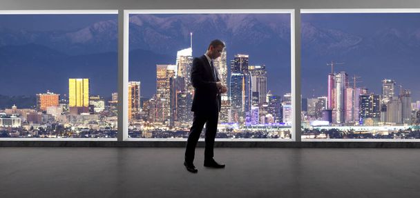 Zakenman in pak kijkend vanuit een kantoorraam naar de gebouwen in het centrum van Los Angeles. De man ziet eruit als een politicus zoals een burgemeester, of een architect of een vastgoedontwikkelaar die werkt in La. - Foto, afbeelding