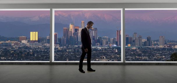 Zakenman in een kantoor kijkend naar het uitzicht op het centrum van Los Angeles. De man ziet eruit als een baas of een regiomanager die in Californië werkt. De achtergrond toont het besneeuwde San Gabriel gebergte in de winter.  - Foto, afbeelding