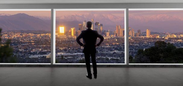 Zakenman in pak kijkend vanuit een kantoorraam naar de gebouwen in het centrum van Los Angeles. De man ziet eruit als een politicus zoals een burgemeester, of een architect of een vastgoedontwikkelaar die werkt in La. - Foto, afbeelding