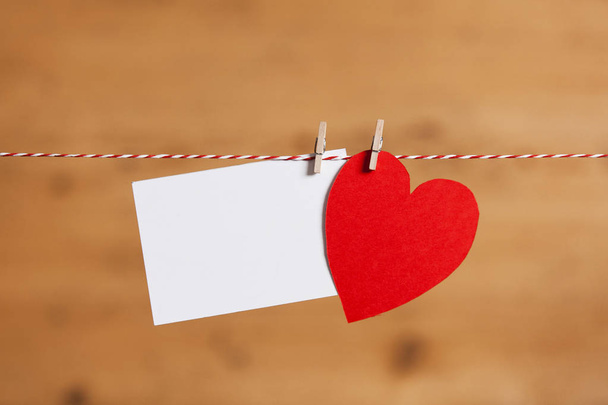Red paper heart and blank white label pegged to a string - Fotografie, Obrázek