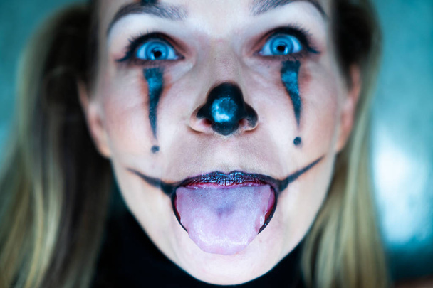 Halloween clown vrouw portret poseren over betonnen muur achtergrond - Foto, afbeelding