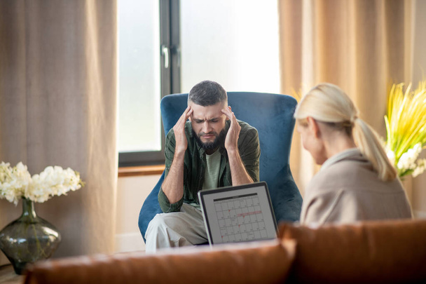 Man having headache while talking to psychologist - Фото, зображення