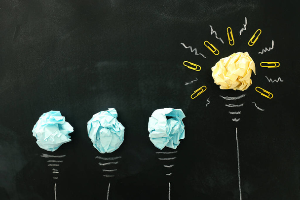 Education concept image. Creative idea and innovation. Crumpled paper as light bulb metaphor over blackboard - Photo, Image