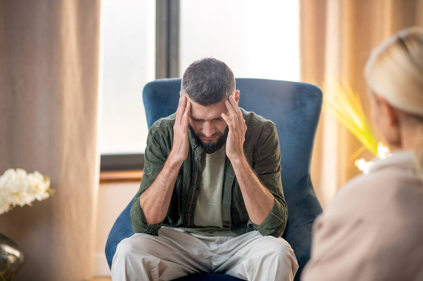 Man suffering from headache while having psychoanalysis - Valokuva, kuva