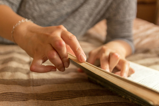 Young woman having rheumatoid is reading a book. Hands and legs are deformed. She feels pain. Selective focus. - Photo, Image