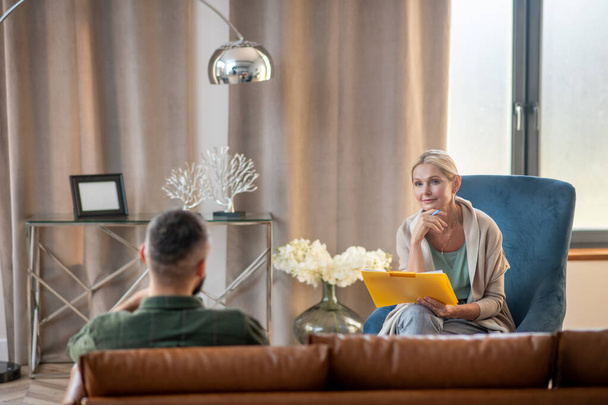 Блондинка психоаналітик розмовляє з пацієнтом у просторій затишній кімнаті
 - Фото, зображення