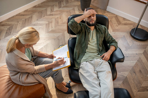 Bearded man touching head while visiting psychologist - Photo, image