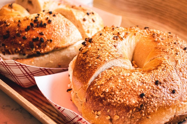 Freshly baked, crunchy typical NYC bagels with sesame, poppyseed topping, cream cheese spread and lox from coffee shop, cafe or bakery in Manhattan, New York City, close up with selective focus. - 写真・画像
