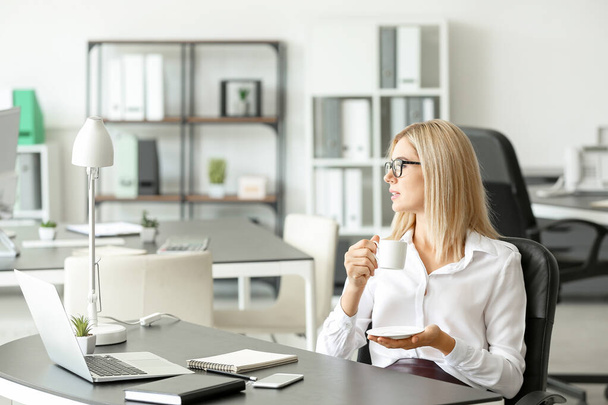 Красива бізнес-леді п'є каву в офісі
 - Фото, зображення