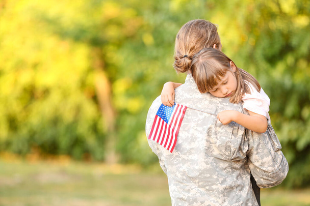 Військовий чоловік обіймає свою маленьку доньку на відкритому повітрі
 - Фото, зображення