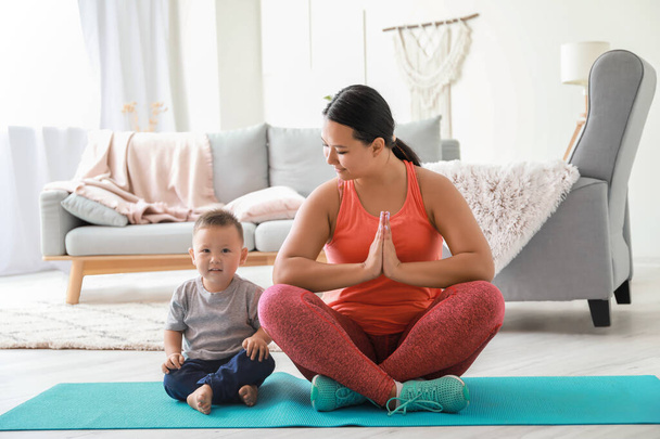 asiatische Mutter mit süßen Baby Junge praktiziert Yoga zu Hause - Foto, Bild