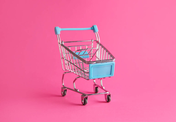 Empty small shopping cart on color background - Фото, изображение