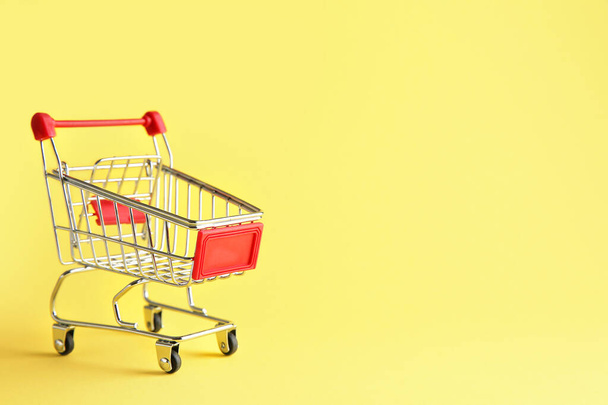Empty small shopping cart on color background - Foto, Imagem