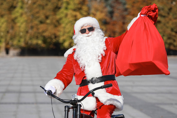 Kerstman met tas paardrijden fiets buiten - Foto, afbeelding