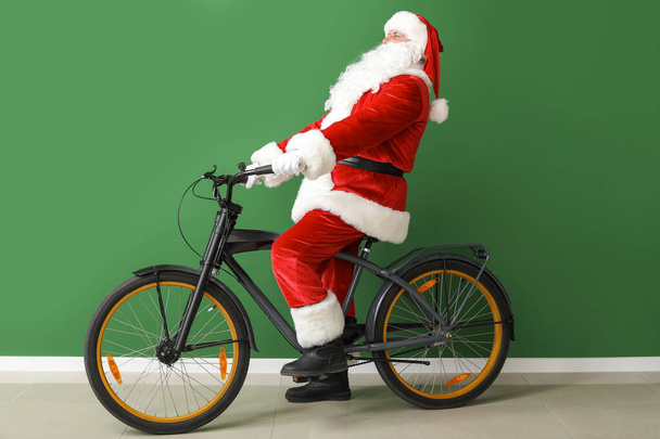 Санта Клаус з велосипедом на кольоровому тлі. - Фото, зображення