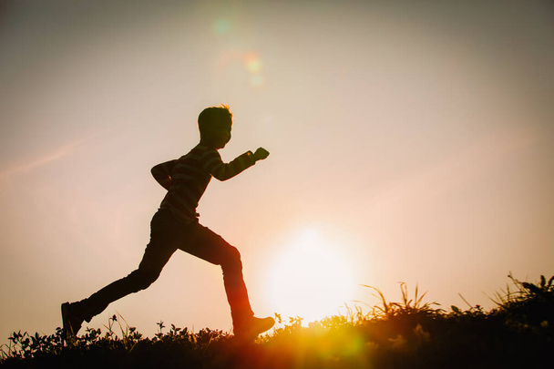 Σιλουέτα του ευτυχισμένου αγοριού τρέχει στο ηλιοβασίλεμα της φύσης - Φωτογραφία, εικόνα