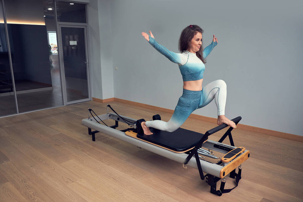 leotard workout pilates training. athletic pilates reformer exercises. pilates machine equipment. young asian woman pilates stretching sport in reformer bed instructor girl in a studio - Photo, Image