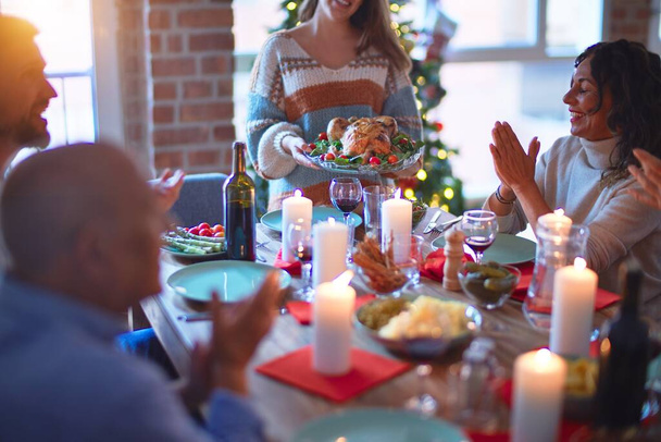 Mooie familie glimlachend gelukkig en zelfverzekerd. Geroosterde kalkoen laten zien en applaudisseren om Kerstmis thuis te vieren - Foto, afbeelding