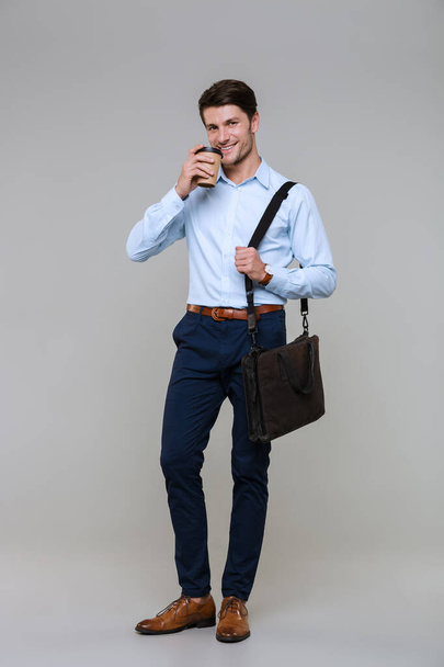 Full length portrait of businessman holding coffee cup and lapto - Foto, immagini