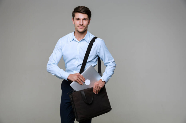 Image of handsome businessman putting laptop computer in bag - Fotografie, Obrázek