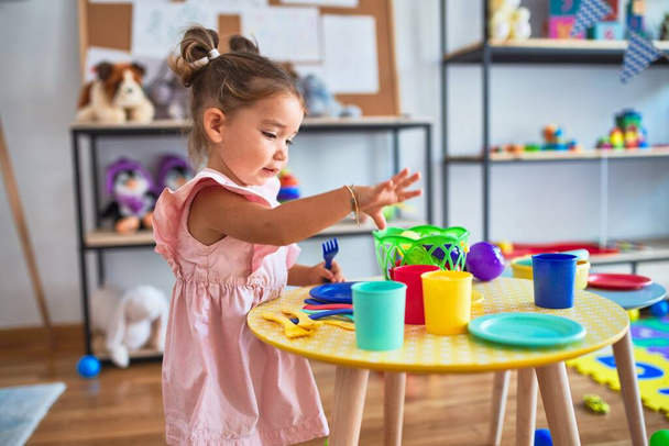 Joven hermoso niño jugando con cubiertos y juguetes de comida en la mesa en kindergaten
 - Foto, Imagen