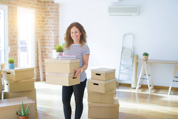 Middle age senior woman smiling happy holding cardboard boxes - Photo, Image