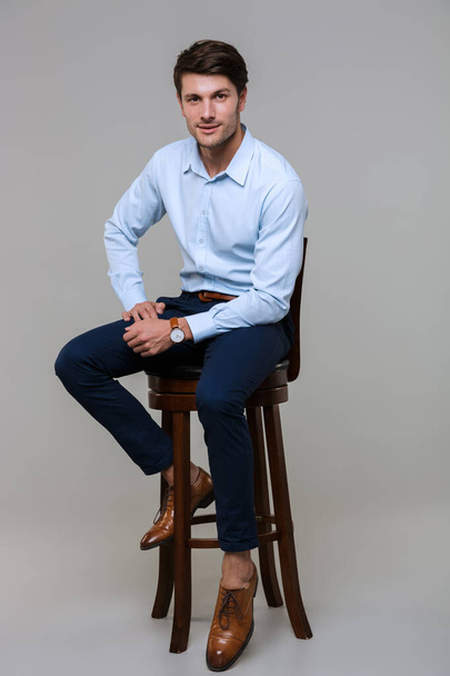 Full length portrait of happy young businessman sitting on chair - Foto, Imagem