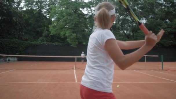 tênis profissional, casal de adolescentes ativos jogar tênis e bola jogando uns aos outros sobre a rede na quadra vermelha sob a chuva
 - Filmagem, Vídeo