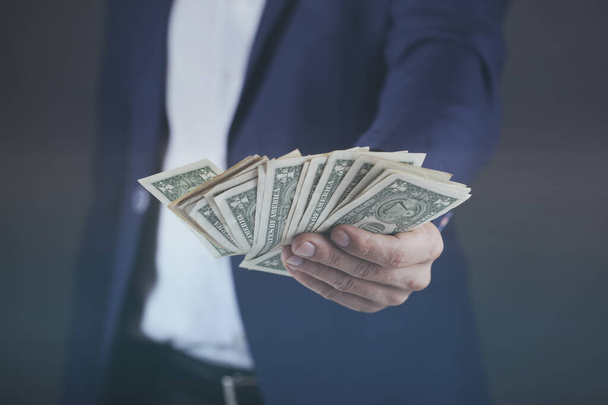 young business man hand holding money on dark background - Foto, Imagen