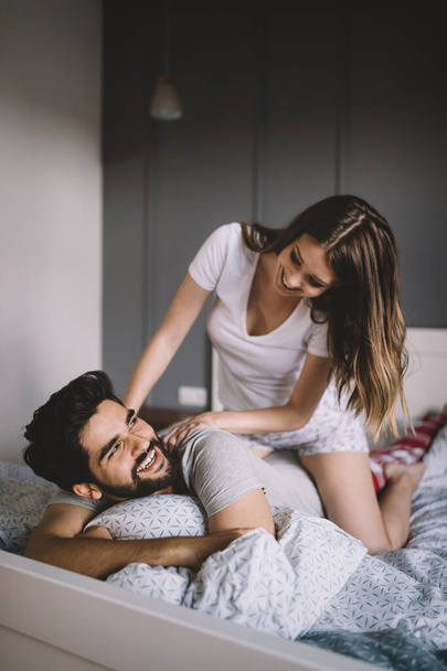Beautiful young woman is doing her handsome boyfriend massage and smiling while they are resting at home - Foto, immagini