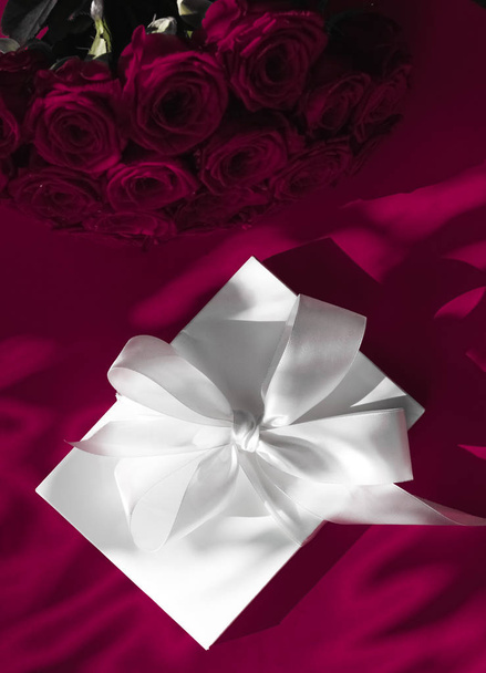Luxury holiday silk gift box and bouquet of roses on wine backgr - Foto, imagen