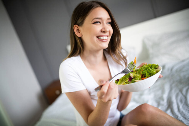 Woman eating healthy salad after working out at home - Foto, Bild