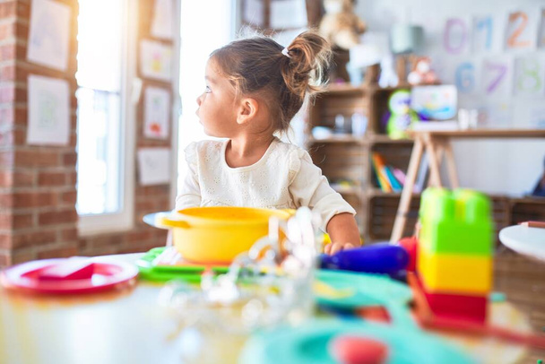 Young beautiful toddler playing with cutlery and food toys on the table at kindergaten - 写真・画像