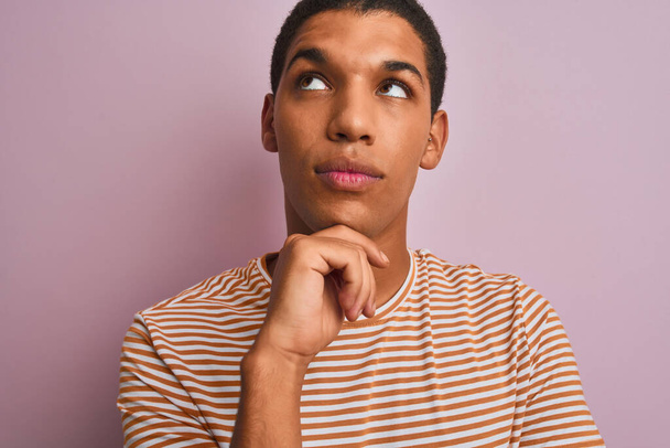 Young handsome arab man wearing striped t-shirt standing over isolated pink background serious face thinking about question, very confused idea - Foto, Imagen