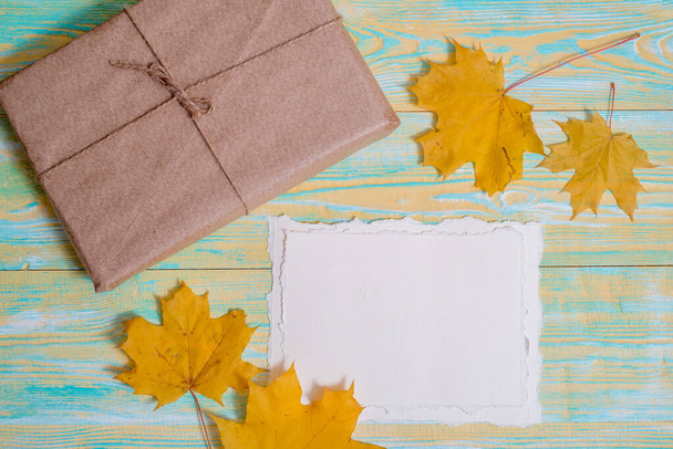 Autumn floral art and craft. gift in craft paper,yellow autumn leaves maple . Orange background. Copy space. Flat lay, top view - Fotoğraf, Görsel