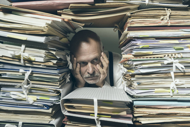 Depressed businessman overwhelmed with paperwork - Фото, зображення