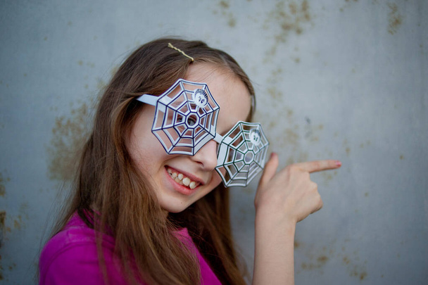 眼鏡をかけた女の子ハロウィンのコンセプト9-10歳の女の子は、ハロウィーンのためのクモのデザインの眼鏡をかけました - 写真・画像
