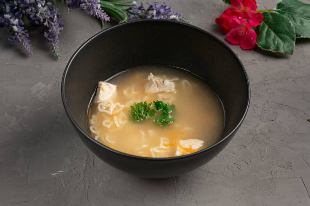 heart-shaped chicken noodle soup in a black plate - Φωτογραφία, εικόνα