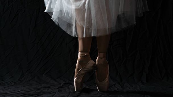 Κοντινό πλάνο των χορευτικών ποδιών της μπαλαρίνας φορώντας λευκό σημείο σε ένα  - Φωτογραφία, εικόνα